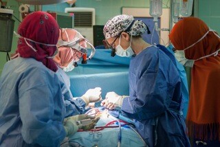 STS Member Dr. Kathleen Fenton (Nicaragua) assists a surgeon in Libya who is performing open heart surgery. Photo courtesy of the Novick Cardiac Alliance. 